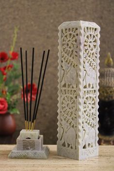 a white vase sitting on top of a wooden table next to a candle holder with reeds in it