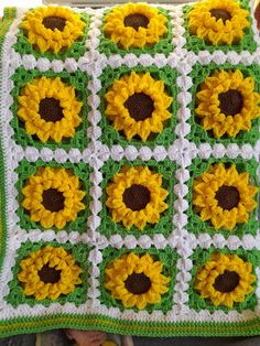 a crocheted blanket with sunflowers on it and a baby in the background