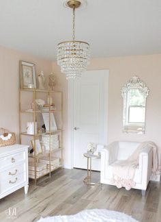 a living room filled with furniture and a chandelier hanging from the ceiling over a wooden floor