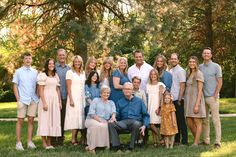 a large group of people posing for a photo in the grass with trees behind them