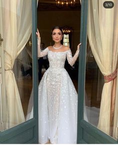 a woman in a white dress is posing for the camera with her hands up and arms out