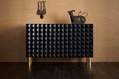 a black and gold sideboard against a wall with jewelry hanging from it's hooks