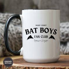 a white and black coffee mug with the words bat boys fan club printed on it