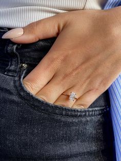 a close up of a person's hand with a diamond ring on their finger