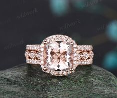 an engagement ring with a large pink diamond surrounded by small diamonds on top of a rock