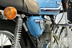 the front end of a blue motorcycle with chrome spokes and an orange light on it