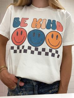 Look super cute and spread good vibes in this trendy retro Smiley Face Be Kind T Shirt!  Spread good vibes in this super soft comfort colors t shirt, and look great doing it! Please note: This item is PRINTED, not embroidered. Printed on a soft, 100% cotton comfort colors t shirt.  SIZING: Our T Shirts are unisex sizing.  We suggest ordering your normal size for a regular fit.  If you want an oversized fit we suggest ordering a size up. Please contact us directly for any custom/bulk orders! T Shirts Trendy, T Shirt Inspiration Design, Groovy T Shirt Designs, 90s Shirt Design, Fun Slogan T-shirt For Everyday, Trendy Relaxed Fit T-shirt With Cartoon Print, Trendy Multicolor T-shirt With Text Print, Trendy Oversized Top With Cartoon Print, Groovy Shirt Designs