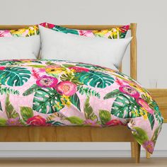 a bed with pink and green floral comforter set on top of wooden headboard