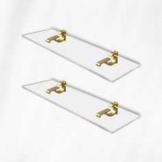 two white trays with gold handles are shown in front of a white wall and one has