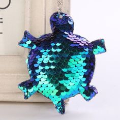 a blue and green turtle shaped keychain hanging from a hook on a chain