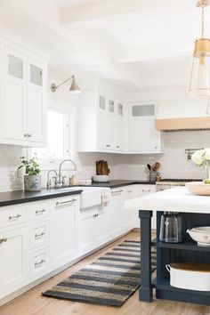 a kitchen with white cabinets and black counter tops, an island in front of the sink