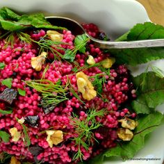 a white bowl filled with lots of food and garnished with green leafy leaves