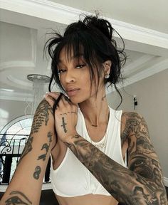 a woman with many tattoos on her arms and arm, posing for the camera in front of a mirror