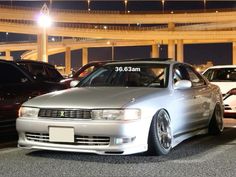 a silver car parked in a parking lot next to other cars on the street at night