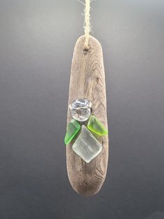 a glass ornament hanging from a rope on a wooden board with sea glass