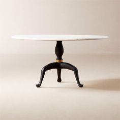 an oval table with black legs and a white marble top, on a beige background