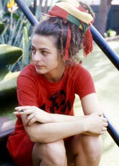 a young woman sitting on the ground with her hands crossed