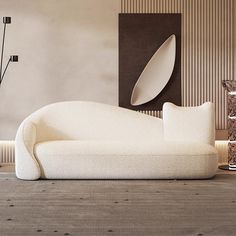 a white couch sitting on top of a carpeted floor next to a vase and lamp