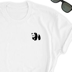 Panda Shirt // Cute Panda T-Shirt // Panda Bear Tee // Panda Top // Panda Tee // Unisex Panda Bear Tee Love Pandas? Who doesn't? Take this beautiful simple Panda icon design to your side everywhere. Friends will love it! This t-shirt feels soft and lightweight, with the right amount of stretch. It's comfortable and flattering for both men and women. * 100% combed and ring-spun cotton (heather colors contain polyester) * Fabric weight: 4.2 oz (142 g/m2) * Shoulder-to-shoulder taping * Side-seamed Simple White Graphic Print T-shirt, Simple White T-shirt With Graphic Print, Simple White Tops With Graphic Print, White T-shirt With Funny Print For Everyday, White Shirt With Funny Print For Everyday, Everyday White Shirt With Funny Print, Casual White Print T-shirt For Everyday, Casual White Printed T-shirt For Everyday, White Basic T-shirt With Funny Print