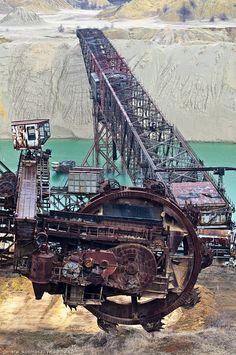 an old train engine sitting on the side of a hill next to a body of water