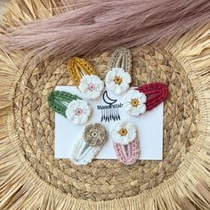 several small crocheted flowers are placed on top of a straw hat with a white card