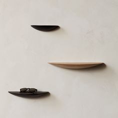 three black shelves on the wall with one shelf holding sunglasses and another shelf above them