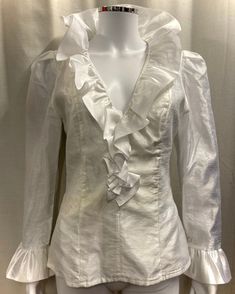 "This is an authentic 1980s ruffle blouse in white Organza. Details in include a deep V neck with large frilled collar, frilled cuffs and a fitted waist. It is fully lined and has a long zip at the back for opening. Size and fit: This top is fitted and there is no stretch to the fabric. The waist measures 28\" and the chest is approximately 36\". It would best fit a UK size 8-10. Condition: This top is in good vintage condition however, there is a pale yellowish stain around the waist area, as shown in the last photo." Victorian Ruffle Blouse, Frill Collar Blouse, White V-neck Blouse With Ruffles, Formal V-neck Blouse With Ruffles, Elegant V-neck Ruffled Blouse, Ruffle Sleeve Blouse With Ruffles For Parties, Party Blouse With Ruffle Sleeves, Chic Fitted Ruffle Blouse, Chic Fitted Blouse With Ruffles