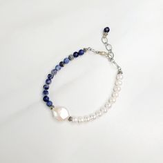 Deep blue sodalite beads are strung opposite luminescent freshwater pearls on our Blue Surf bracelet. One large coin shaped freshwater pearl divides the two. Handmade in the United States, a matching necklace is available. Features: - Sodalite Beads - Freshwater Pearls - Coin Shaped Freshwater Pearl - Etched Silver Plated Cable Chain - Lobster Claw Clasp - Extension - Handmade in the United States Dimensions: - Length: 7.5" - Extension: 1.0" - Total Length: 8.5" - Sodalite Beads: 6mm - Freshwate Blue Pearl Bracelet With Natural Round Beads, Blue Pearl Bracelet With Natural Stones, Adjustable Blue Pearl Bracelet With Natural Stones, Adjustable Blue Pearl Drop Jewelry, Surf Bracelet, Blue Sodalite, Matching Necklaces, Cable Chain, Lobster Claw