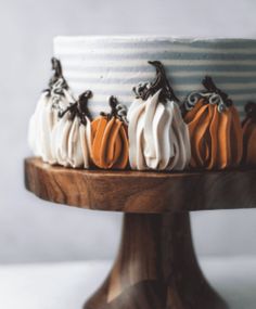 a cake decorated with pumpkins on a wooden stand