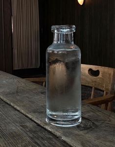 a glass bottle filled with water sitting on top of a wooden table next to a chair