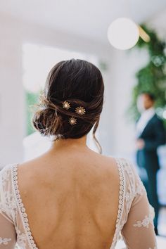 the back of a woman's dress with gold hair pins on her left shoulder