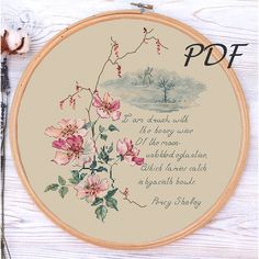 a cross stitch pattern with pink flowers and a poem written in it on a white wooden background