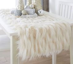 the table is decorated with silver ornaments and white sheepskins, along with other holiday decorations