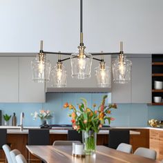 a dining room table with chairs and lights hanging from it's centerpieces