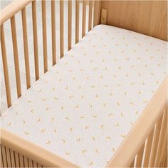 a baby crib with a white and gold sheet on it's bottom half