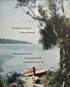 a woman sitting on the edge of a cliff next to a body of water with a boat in it