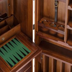 an open bookcase with several pieces of wood in it and one section has a green rug on the floor