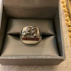 a close up of a ring in a box on a table with gold trimming