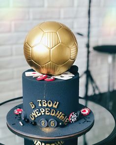 a birthday cake with a gold soccer ball on top and other decorations around the base