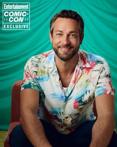 a man sitting on top of a chair in front of a green background with the words comic con