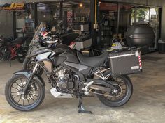 a motorcycle parked in front of a building with other motorcycles and equipment on display behind it