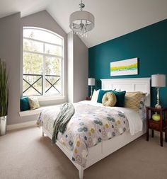 a bedroom with teal walls and white bedding in the center, along with a chandelier hanging from the ceiling