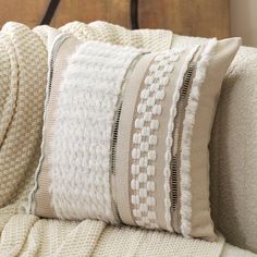 a close up of a pillow on a couch with a wooden headboard in the background