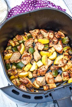 a pan filled with chicken and veggies on top of a wooden table