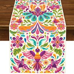 an image of a table runner with colorful flowers and birds on the front, in bright colors