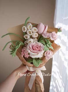 a person holding a bouquet of flowers in front of a window