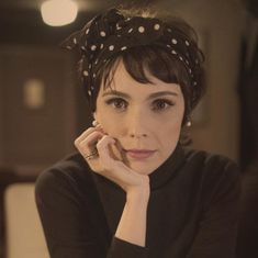 a woman wearing a polka dot headband with her hand on her chin looking at the camera