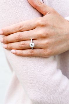 a woman's hand with a diamond ring on her stomach, wearing a white sweater