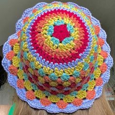 three crocheted hats are stacked on top of each other, one is multicolored