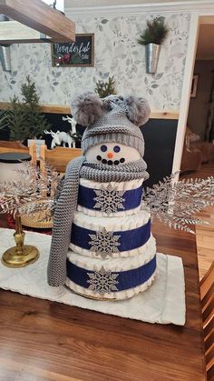 a snowman made out of sweaters and hats on top of a wooden table